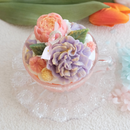 Miss Blooms Flower Premium Vintage Tea Cup Candle with purple carnation, peach peony and green leaves in a crystal teacup on saucer