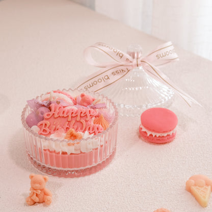 Miss Blooms Sweet Treats Happy Birthday Bowl Candle in ribbed glass bowl — Happy Birthday wax lettering, bear and macaron decorations, glass lid and Miss Blooms ribbon alongside pink macaron