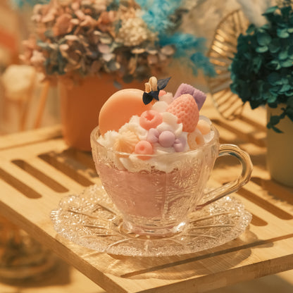 Miss Blooms Gourmet Dessert Candle in Vintage Teacup Set — warm golden hour light on vintage glass teacup with macarons, raspberry and flower wax toppings, dried floral backdrop