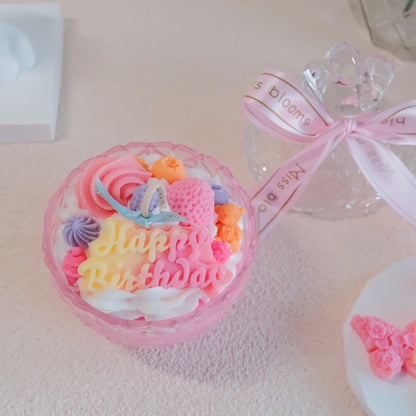 Miss Blooms Sweet Treats Happy Birthday Candle in pink faceted glass bowl with Happy Birthday wax lettering and colourful macaron, flower and berry decorations, Miss Blooms ribbon