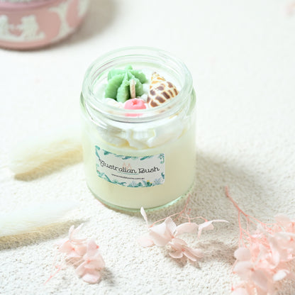 Close-up of Miss Blooms Small Jar Candle showing colourful wax macaron, donut and floral toppings on pastel soy wax