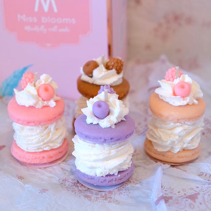 Miss Blooms Macaron Candles in pink, lavender and peach — stacked macaron shapes with cream and berry wax details, Miss Blooms gift box in background