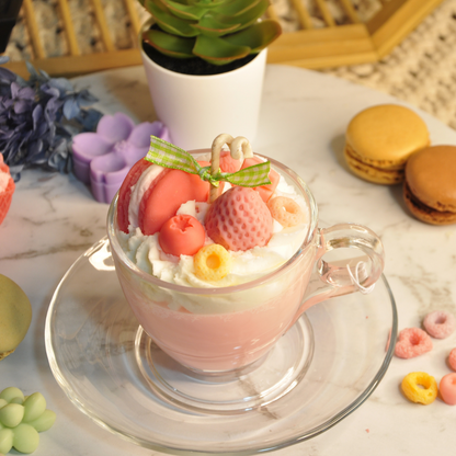 Miss Blooms Sweet Treats Tea Cup Candle in pink glass teacup with saucer, topped with strawberry, macaron and whipped cream wax decorations on marble surface